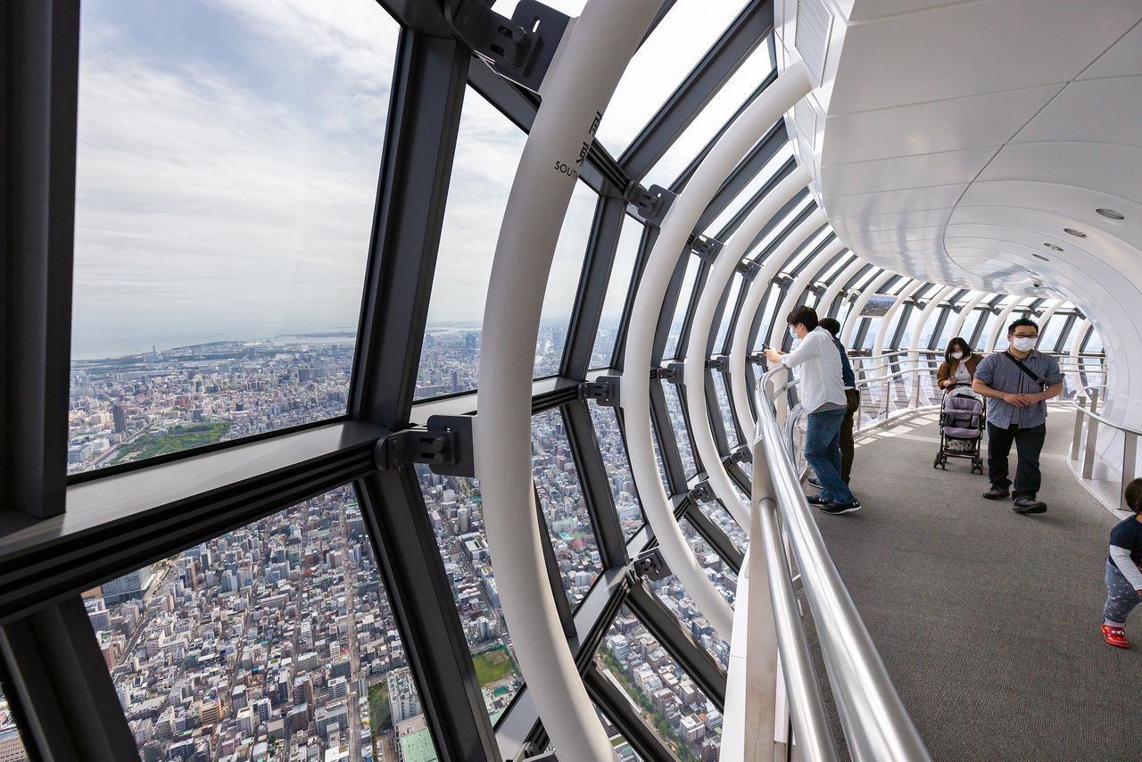 Visitors take in the view from the Tenbō Galleria observation deck 450 meters up, which features an upward-sloping floor meant to give the impression of strolling in the clouds.