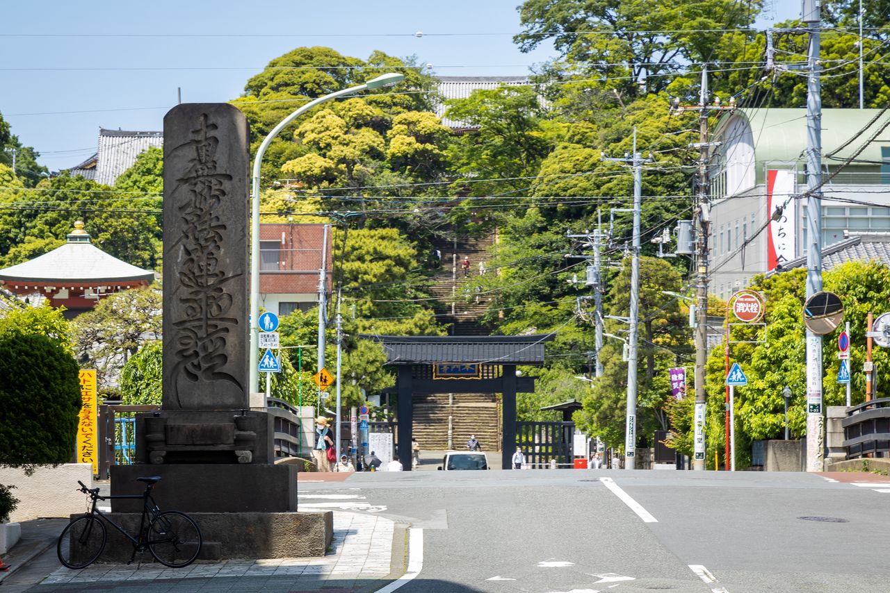 The temple buildings are visible from Ryōzen Bridge, which spans the Nomi River. A stone pillar engraved with the words Namu Myōhō Renge Kyō stands at the site.