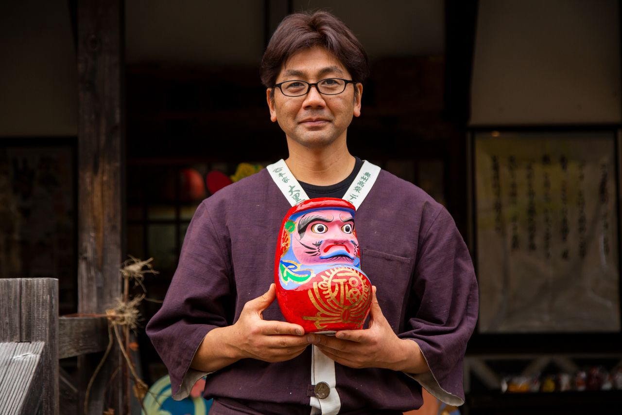 Hashimoto Shōichi holding a Miharu-hariko daruma doll.