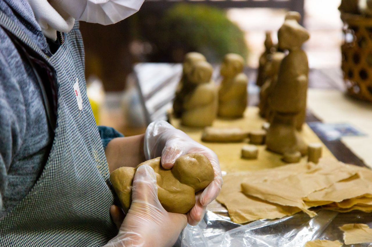 Torn pieces of wet washi are pressed firmly onto a wooden form.