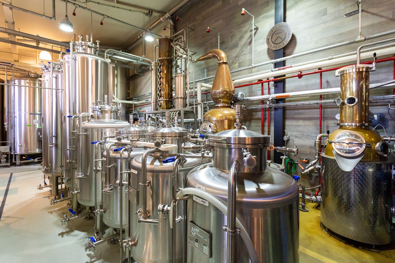 The tanks lined up in the foreground contain individual elements. The copper still in the center background plays a central role in the gin-making process.