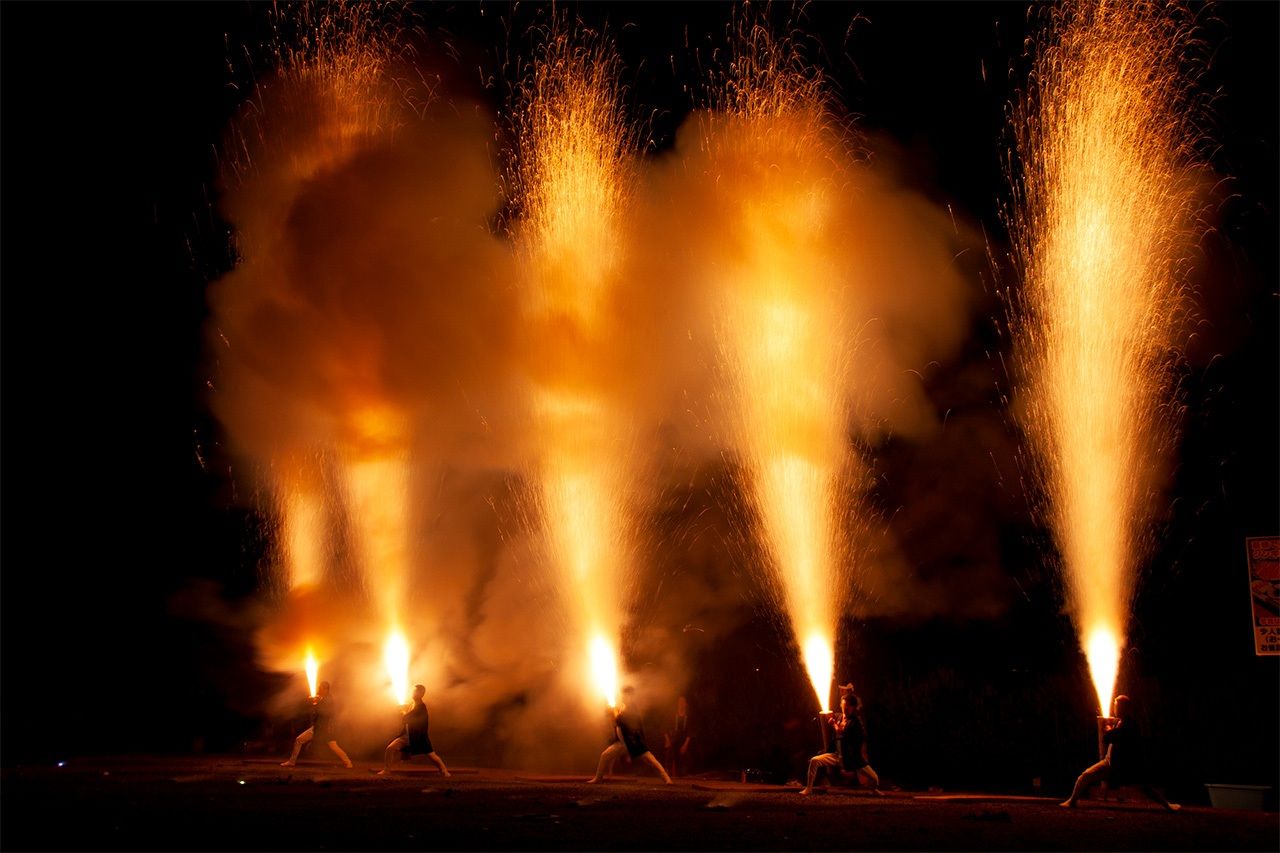 Performers show their mettle by holding flaming <em>tezutsu</em> cannons in one of the main attractions of the Toyohashi Gion Festival. (© Pixta)