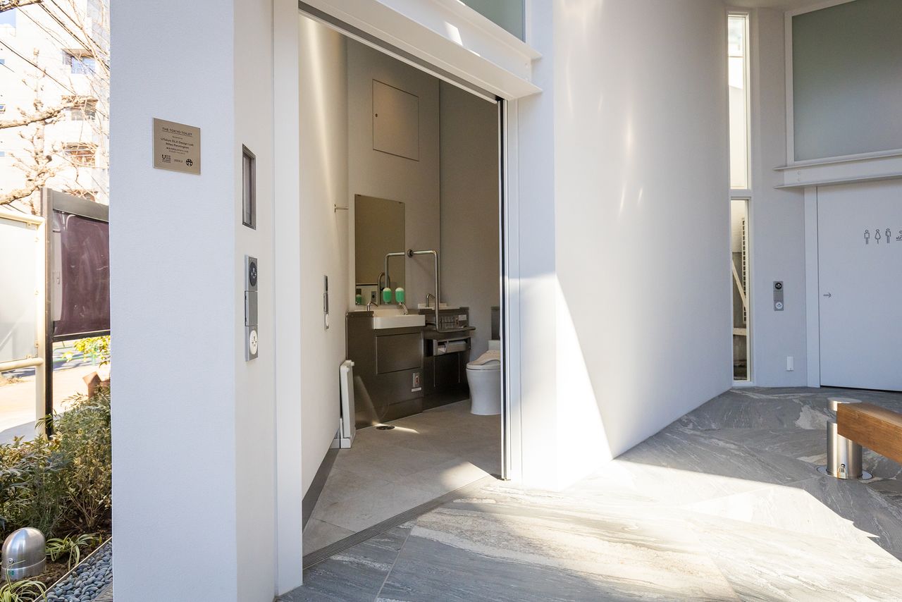 This toilet provides a full range of amenities, including facilities for ostomates, wall-mounted baby seats, and fold-down boards allowing users to remove footwear and stand on a clean surface when changing clothes inside a cubicle.