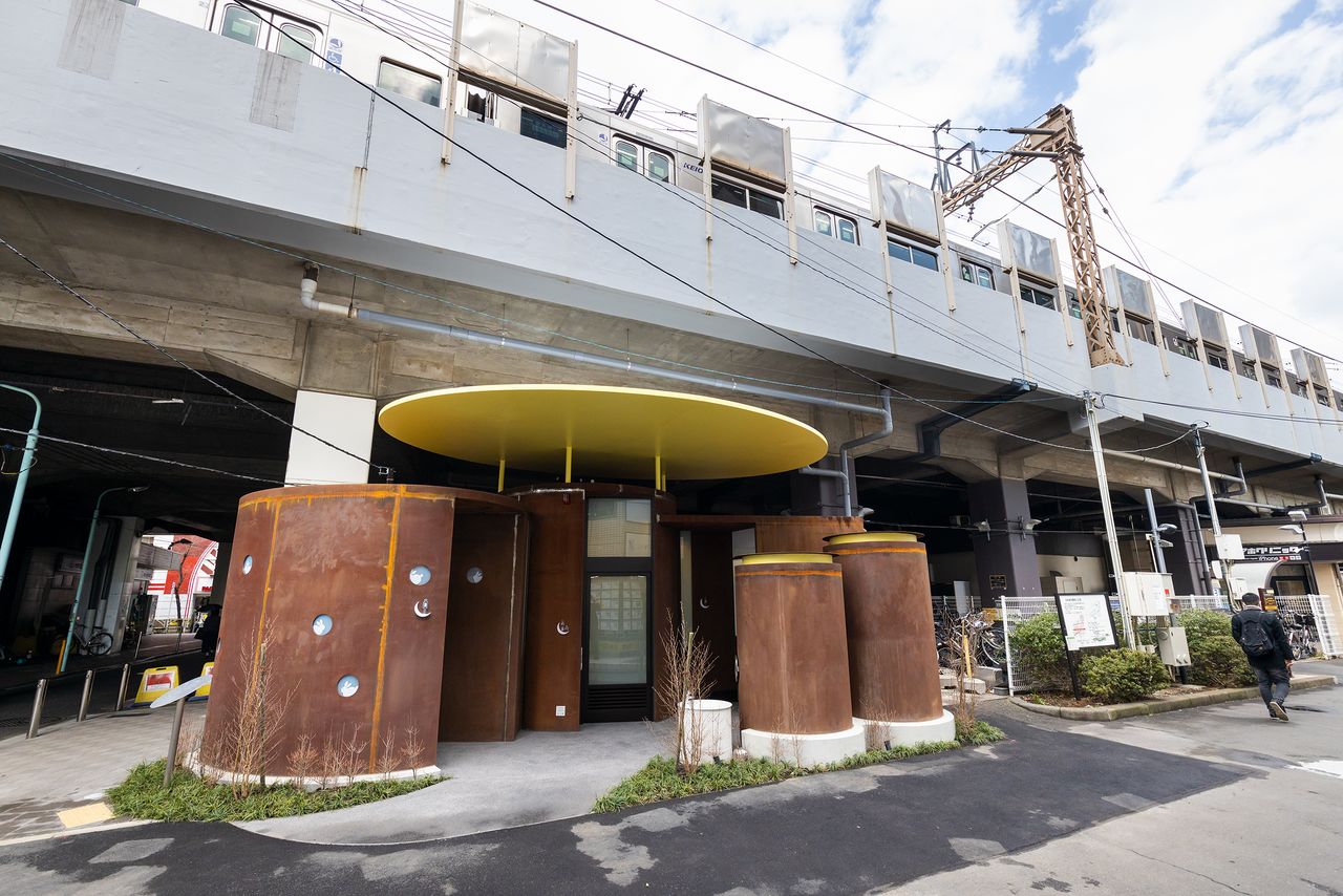 The Sasazuka Greenway Public Toilet under the Keiō Line railway tracks stands out with its rust-colored cylinders.