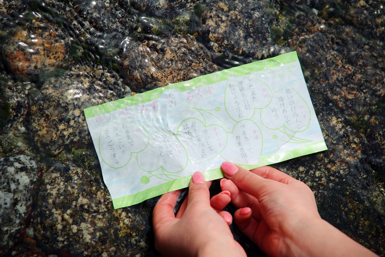 This special fortune-telling slip, sold at the Mitarashi shrine office, reveals its message when dipped in water. The paper is watermarked with the shrine’s futaba-aoi crest. What fortune will the water reveal? (© Edit Plus)