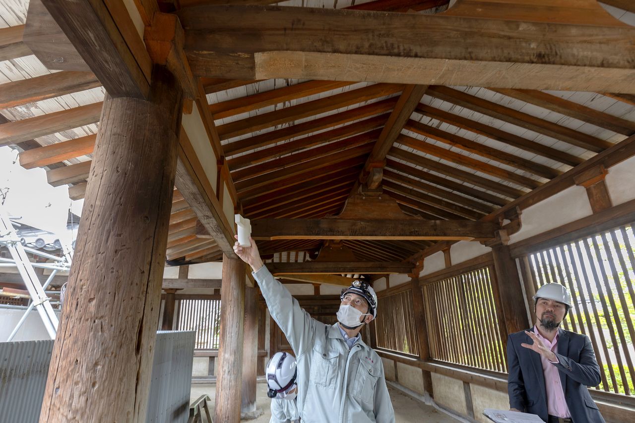 Yoshida uses a model to explain how the corridor is built. Pillars and beams are connected using wood joinery, a nail-free technique characteristic of Japanese architecture. (© Kinoshita Kiyotaka)