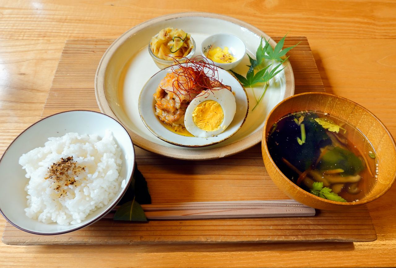 The rice pictured here is grown locally, and a locally sourced leaf serves as a chopstick rest. (© Fujiwara Tomoyuki)