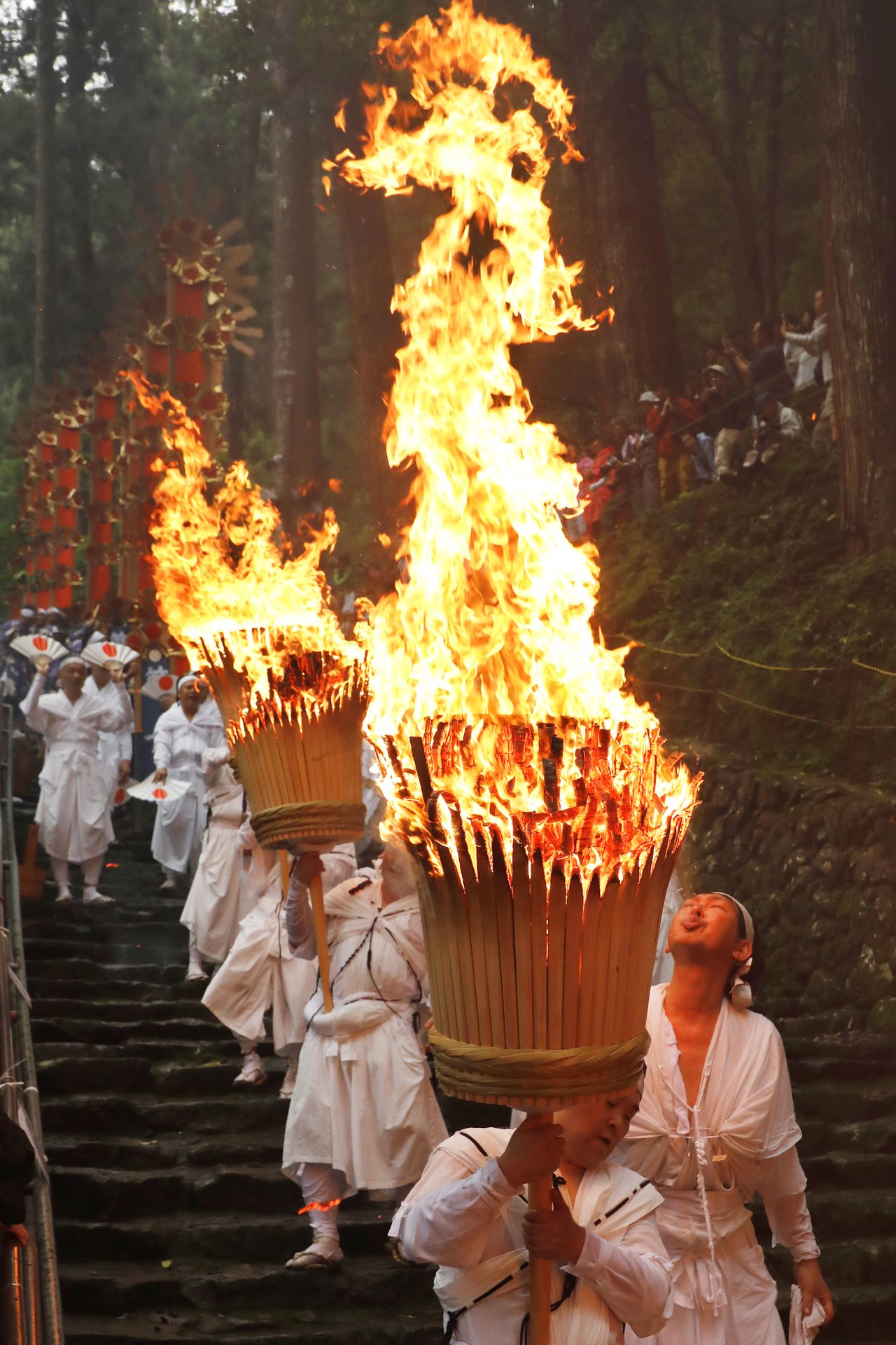Parishioners carry torches to purify the 133 stone steps to the shrine. (© Haga Library)