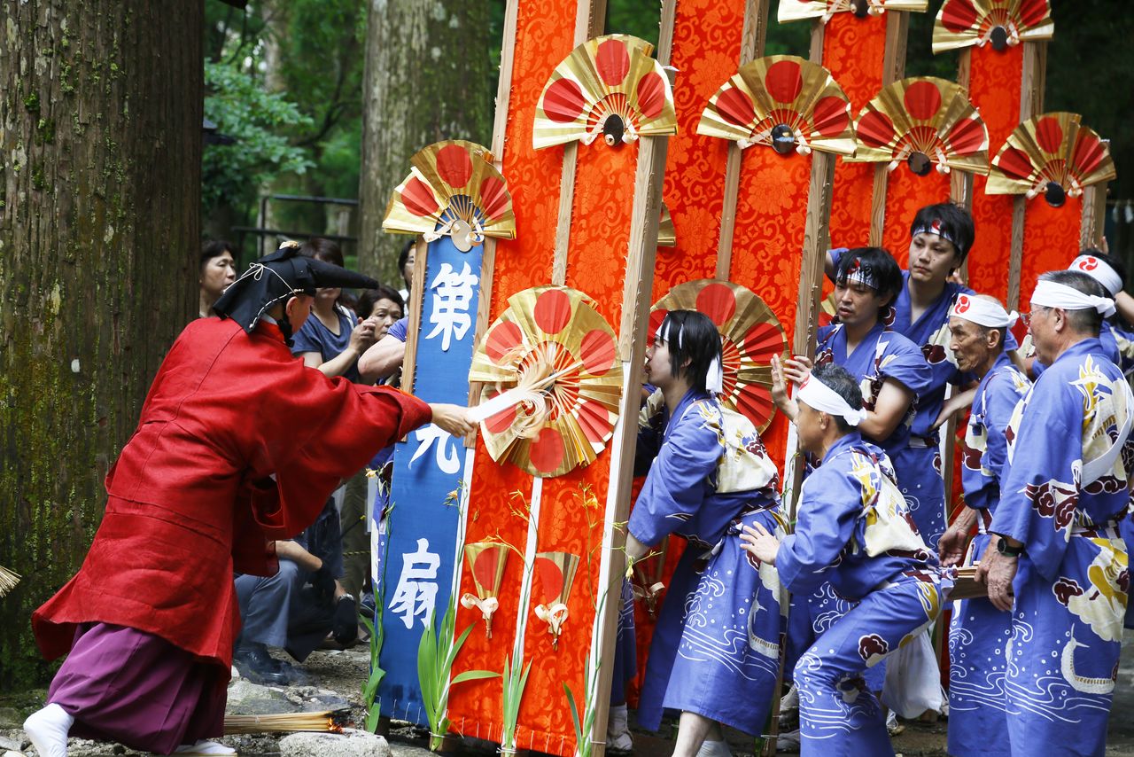 After a shrine priest taps the 12 mikoshi with a folding fan, they are carried to the base of the waterfall. (© Haga Library)