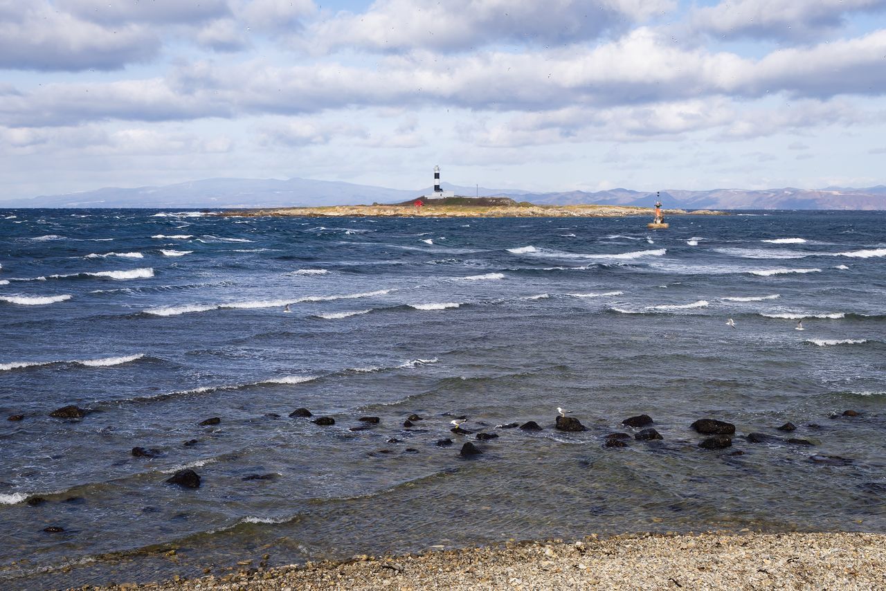 View of the Tsugaru Strait from Cape Ōma at the northern end of the Shimokita Peninsula. The land area in the background behind the Cape Ōma Lighthouse (Benten Island) is the city of Hakodate, Hokkaidō, where the Toi fishing port is located. (© Nippon.com)