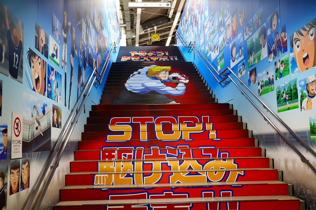 A stairway to a Yotsugi Station platform. The walls are emblazoned with characters from Captain Tsubasa. (© Matsumoto Sōichi)