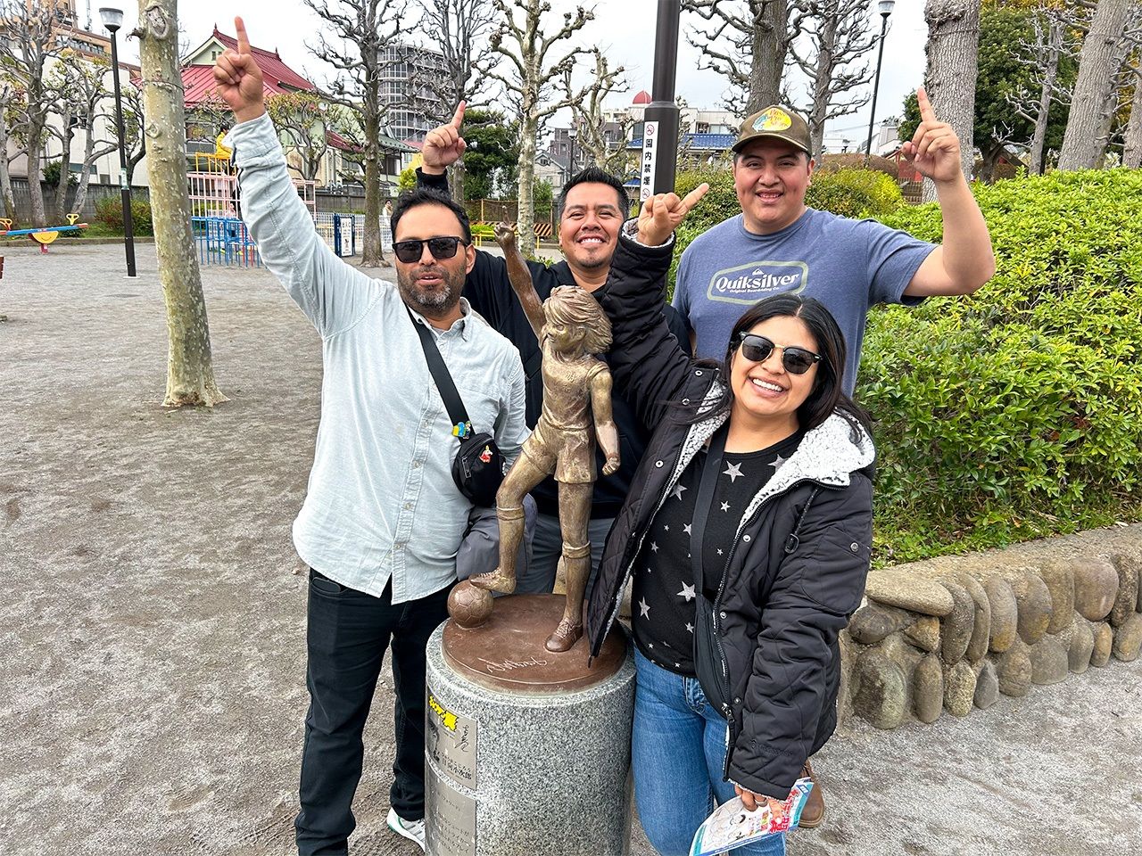 Noé Gomez (rear center) and his friends pose for a photo with a statue of Ōzora Tsubasa’s rival, Hyūga Kojirō, in Katsushika’s Yotsugi Park. (© Matsumoto Sōichi)
