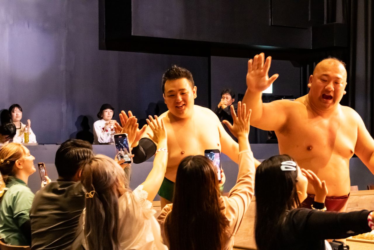 Spectators are allowed to give high-fives and pose for photos with wrestlers even during performances. There is also plenty of time afterwards for meet-and-greets. (© Nippon.com)