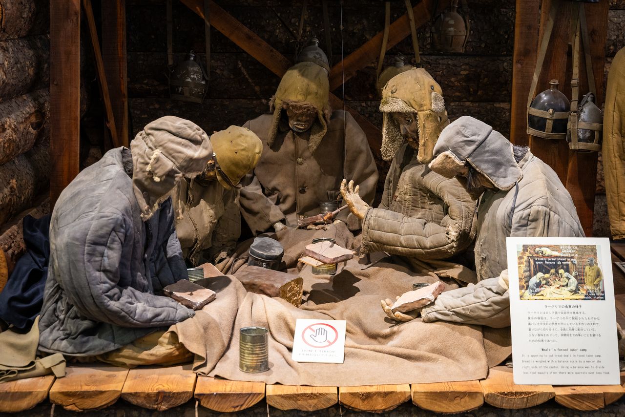 A meal scene at a labor camp. To prevent disputes, bread was cut into equal portions after being weighed on a handmade scale. (© Nippon.com)