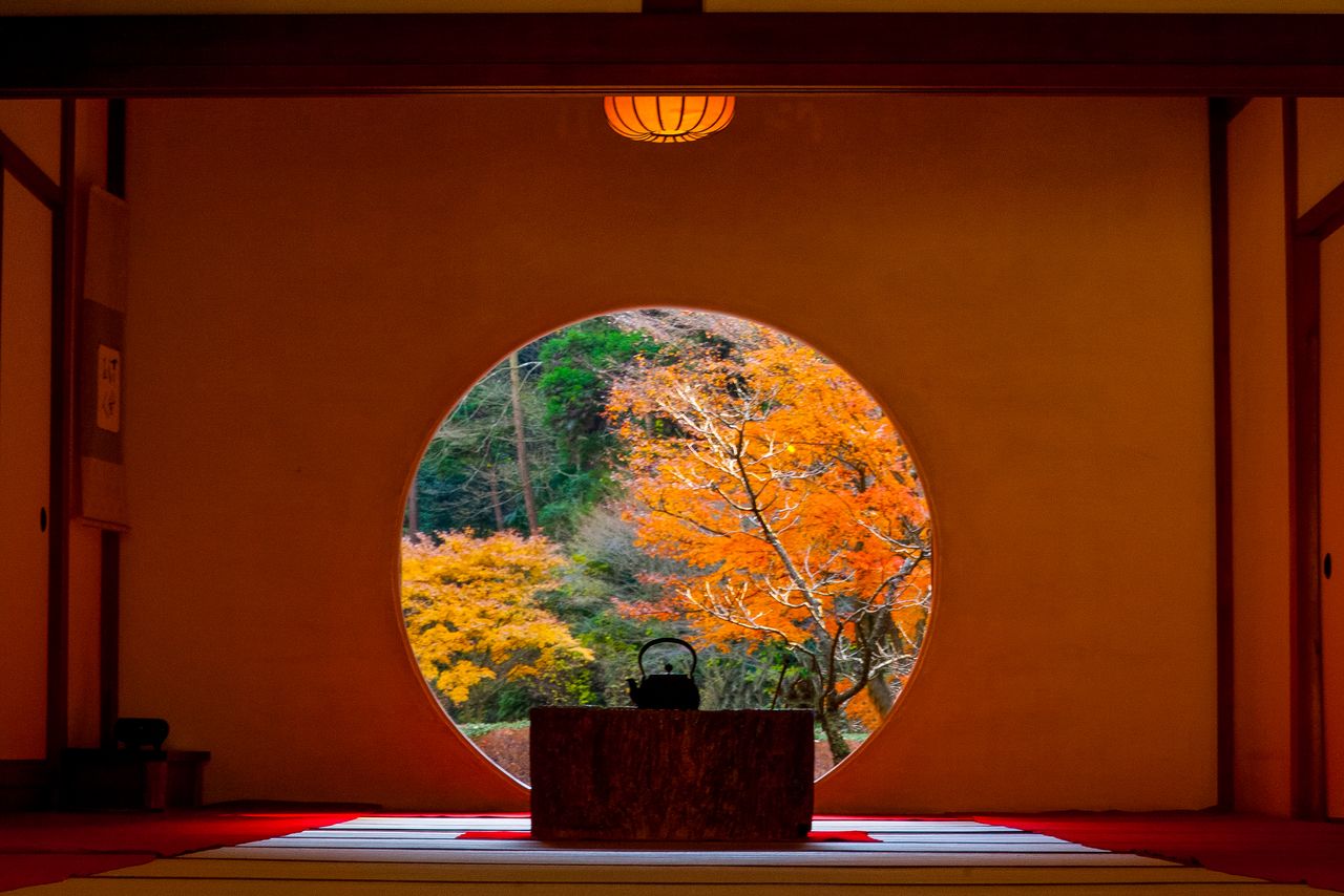 Autumn’s brilliant colors glow through Meigetsuin’s “window of enlightenment.” (© Harada Hiroshi)