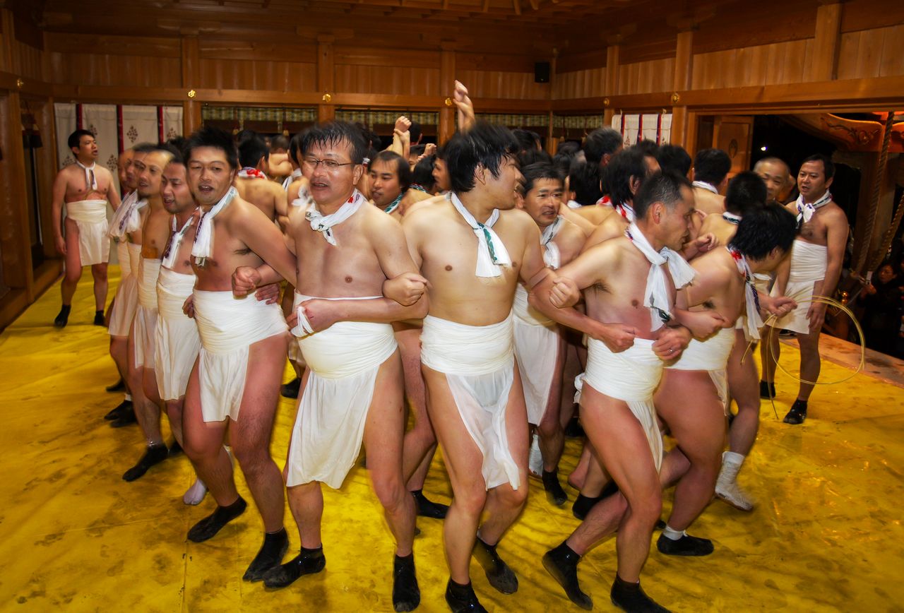 The groom, with only his upraised arms showing, is boxed in on all sides by shrine parishioners. (© Haga Library)