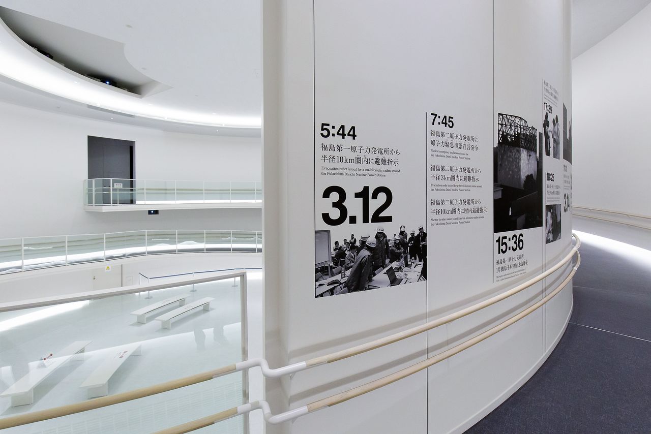 Photographs displayed on the wall of a ramp that curves around the theater. The timeline starts at 1967, when the construction of the first nuclear reactor at Fukushima Daiichi began.