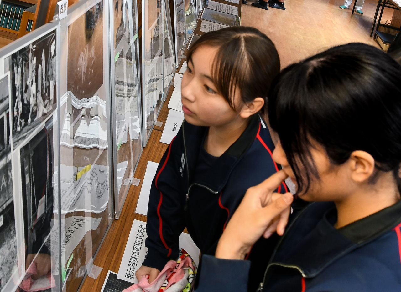 Students closely examine the photos at China Junior High School. (© Sakae Makiko)