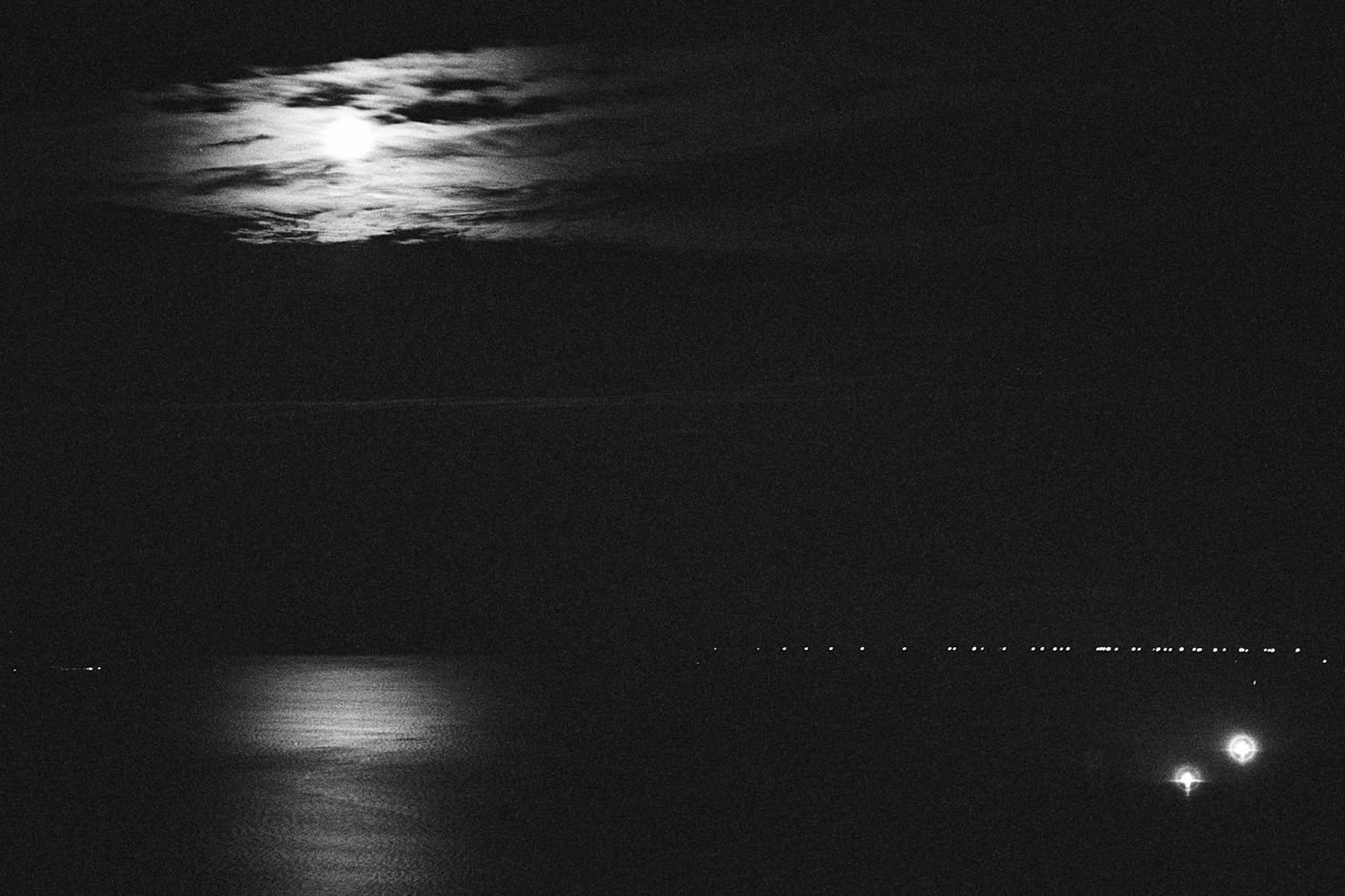 The moon through clouds over a calm Tsugaru Strait with fishing fires. (2008) 
