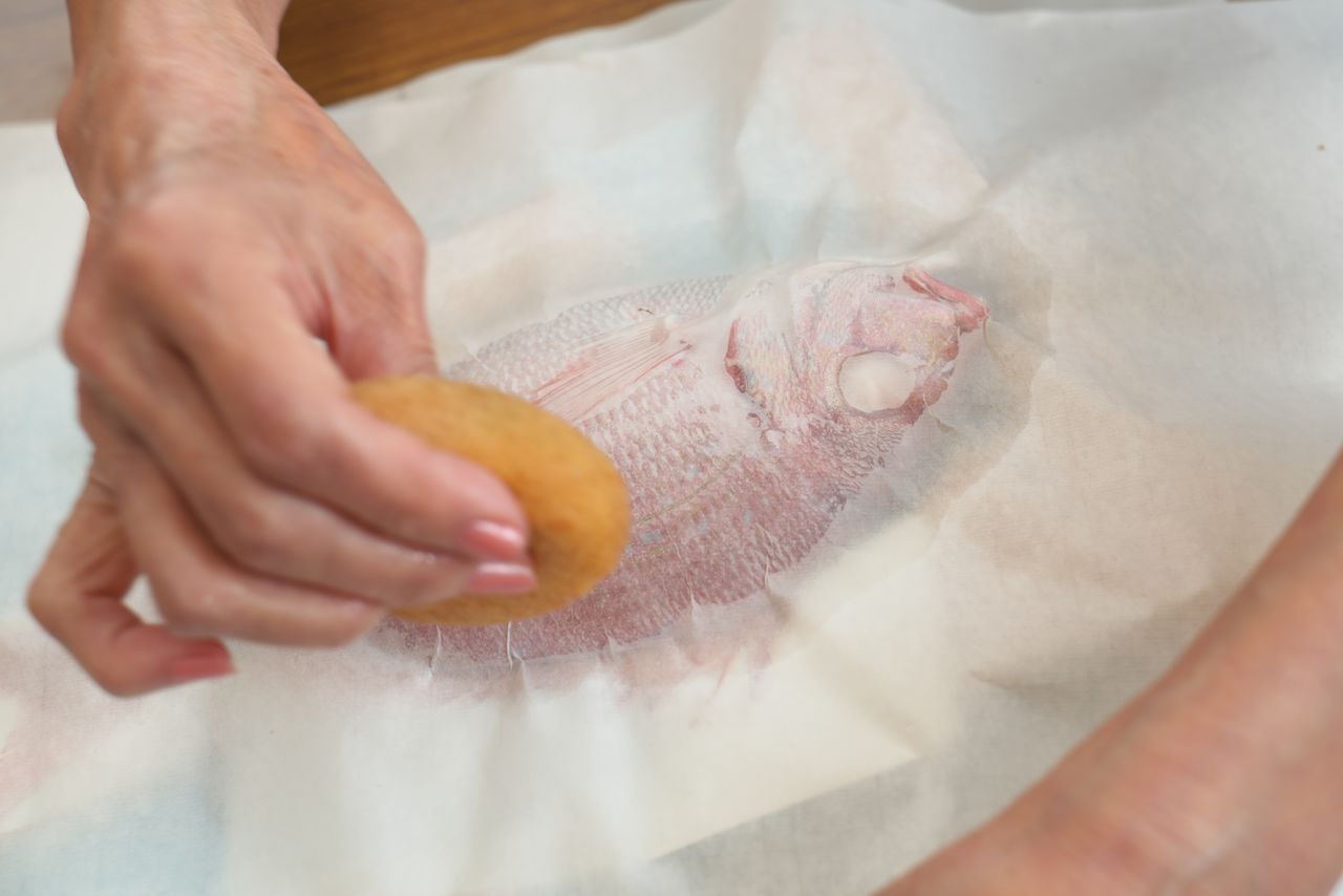 The washi is pressed closely to the fish and excess moisture wiped away. (© Nomura Kazuyuki)