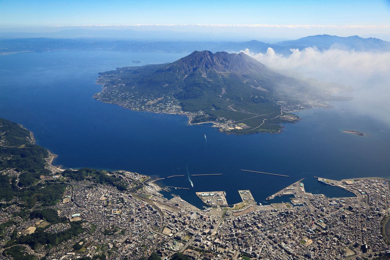 An aerial view of Sakurajima in Kinkō Bay with Kagoshima in the foreground.