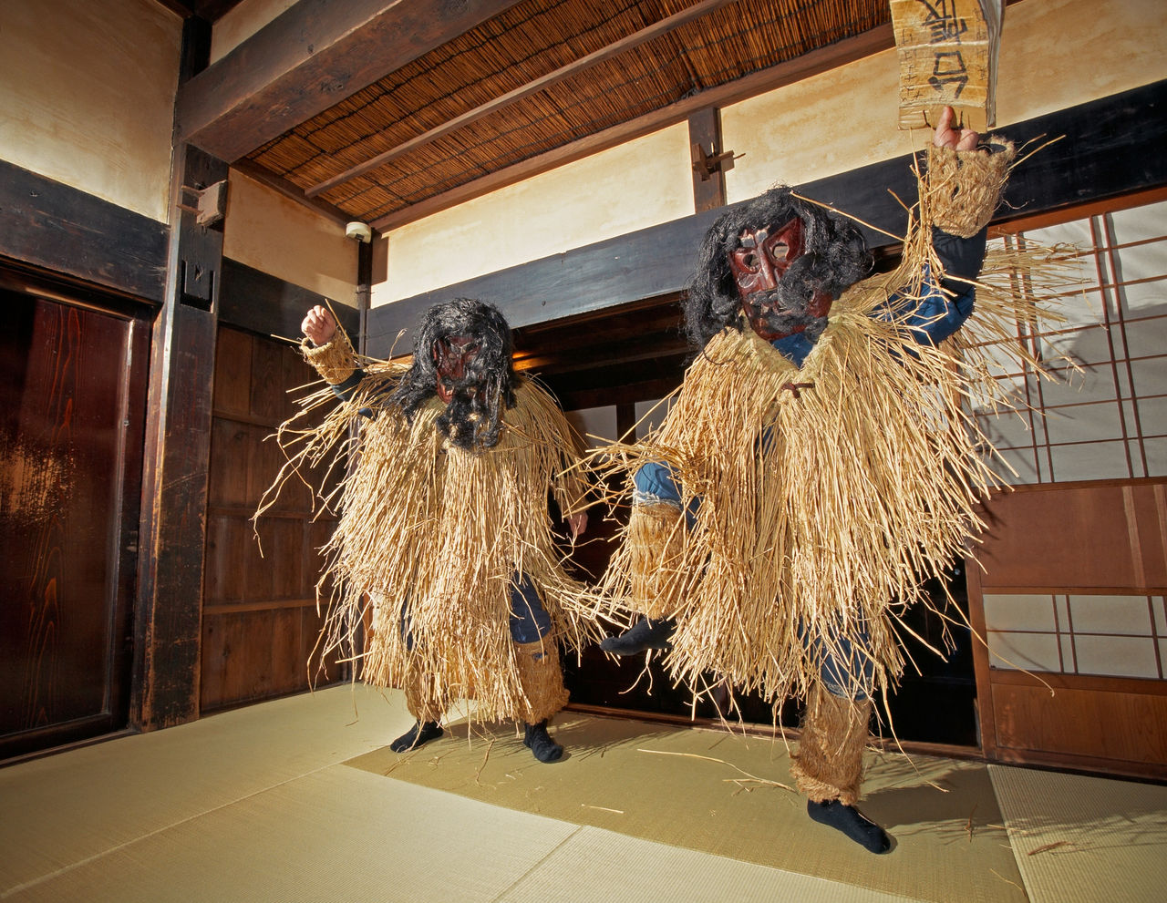 <em>Namahage</em> dressed in straw capes dance in a house they have come to bless.