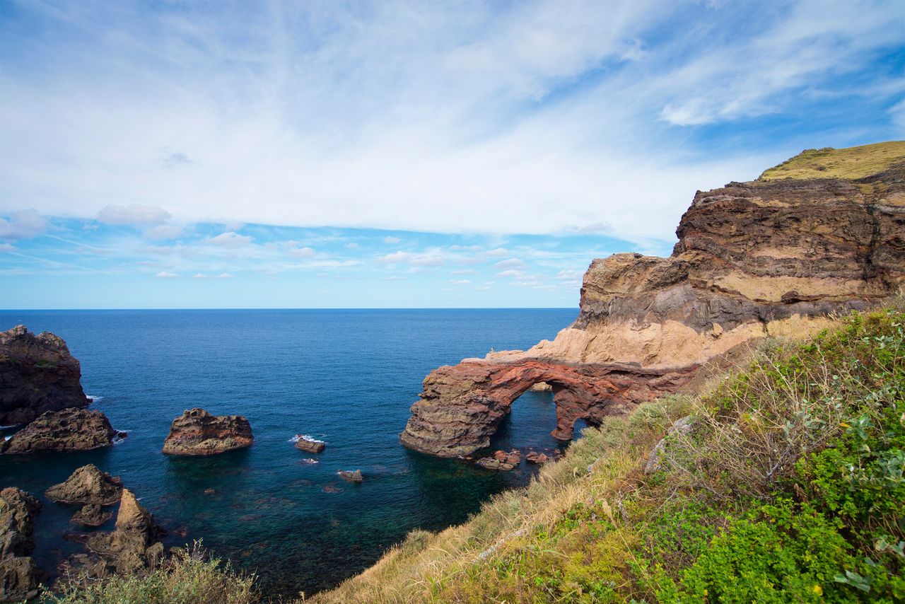 The Kuniga coast, on the western side of Dōzen, features sheer cliffs and curious rock formations such as Tsūtenkyō (photo center). (© Pixta)