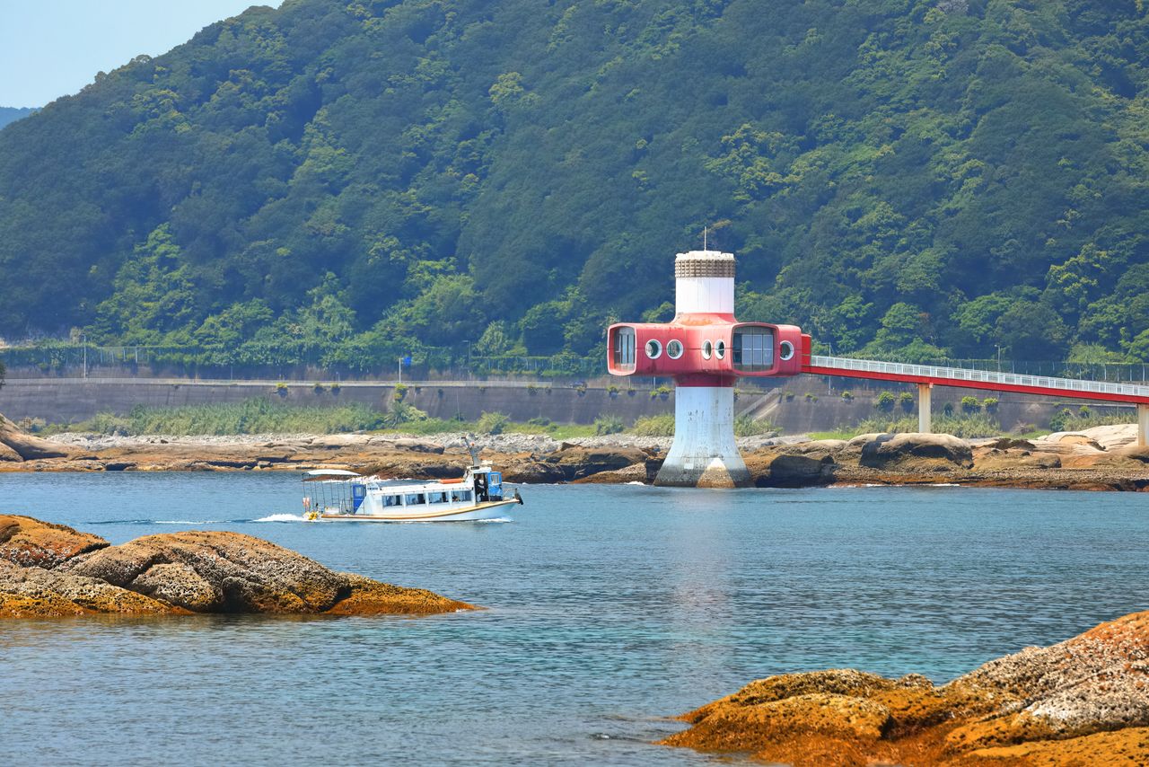 A glass-bottomed tour boat sails in front of the Ashizuri Underwater Aquarium. (© Pixta)