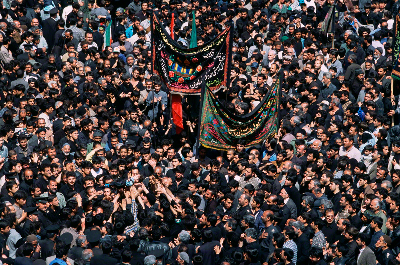 Men mourn the death of Imam Husayn, who was killed in the Battle of Karbala, Iraq. Mourners hold up a small child representing Husayn’s youngest son. Mashhad, Iran, 2001. (From Persia)