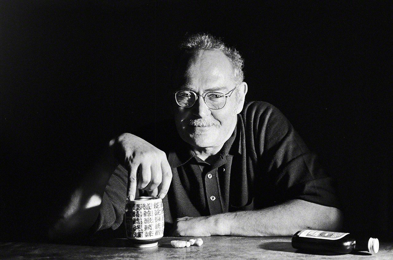 Eugene Smith in 1974, drinking whisky out of a teacup from a sushi shop.