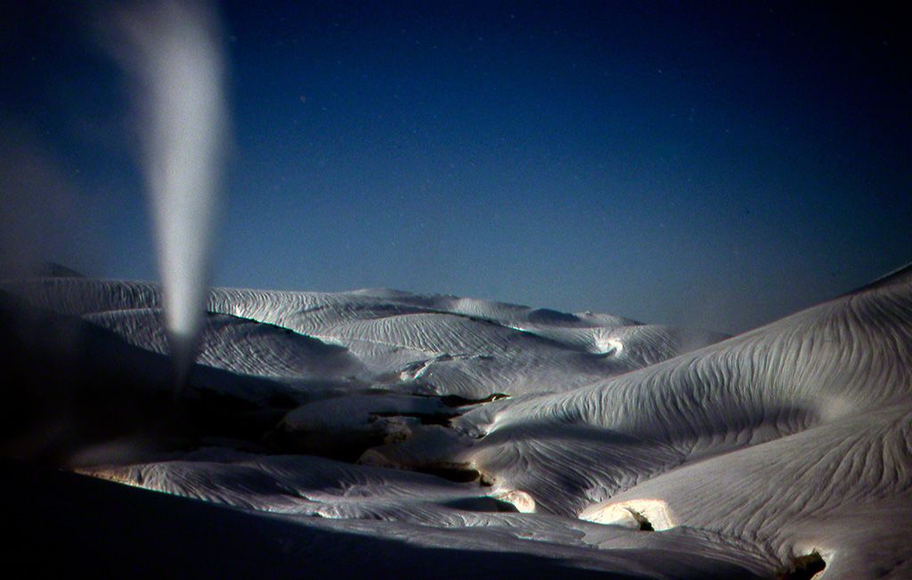 A geyser bursts from the Jigokudani valley into the moonlit sky (April).