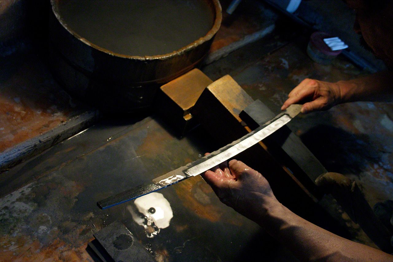 After firing the sword, Miyairi checks the blade carefully to inspect the “hamon” patterning.