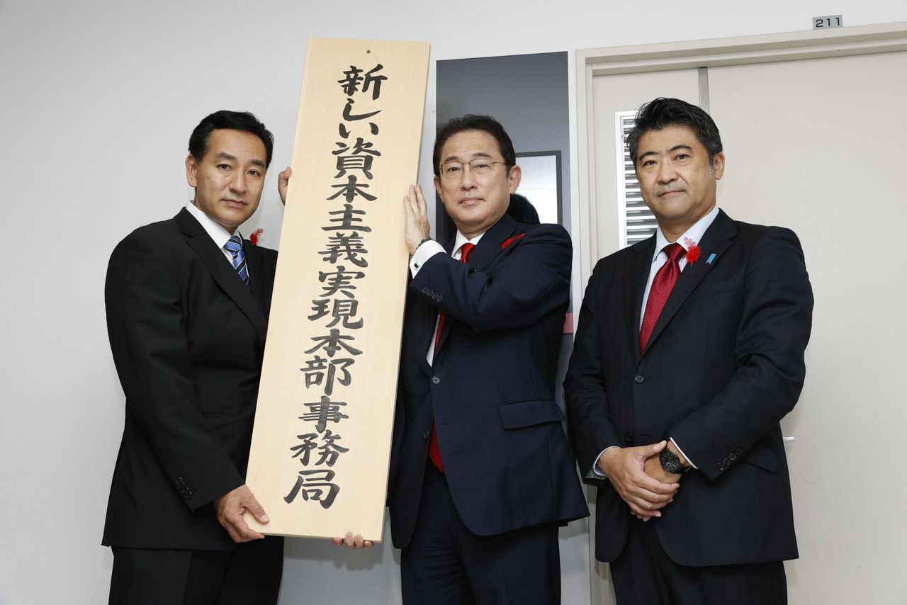 From left, Minister for Economic Revitalization Yamagiwa Daishirō, Prime Minister Kishida Fumio, and Deputy Chief Cabinet Secretary Kihara Seiji present a sign marking the headquarters for the policy unit the New Form of Capitalism Realization in Nagatachō, Tokyo, on October 15, 2021. (© Jiji)