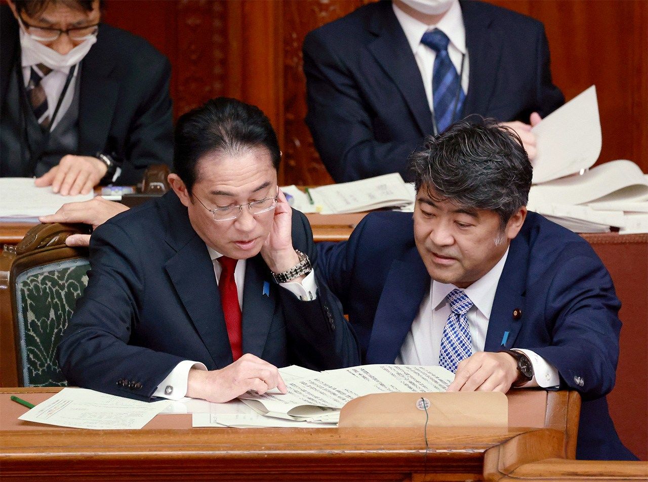 Prime Minister Kishida Fumio (left) and Deputy Chief Cabinet Secretary Kihara Seiji talk in the Diet during a plenary session after the announcement of the three key security documents at the House of Representatives, April 4, 2023. (© Jiji)