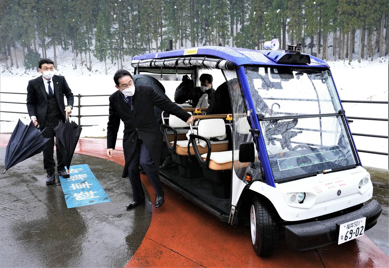 Prime Minister Kishida Fumio, center, steps out of a self-driving cart after going for a test ride on Eiheiji’s transportation service on February 4, 2023. (© Jiji)