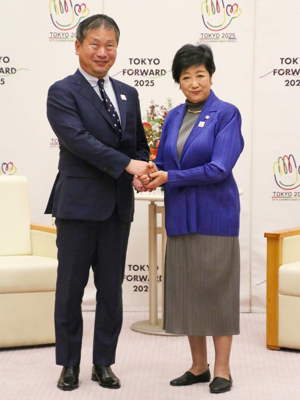 Japan Sports Agency Commissioner Kawai Jun’ichi, left, shaking hands with Tokyo Governor Koike Yuriko on October 24. (© Jiji)