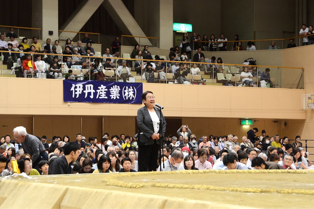 Takarazuka Mayor Nakagawa Tomoko speaks from a platform below the ring during a 2018 regional sumō tour. (© AFP/Jiji)
