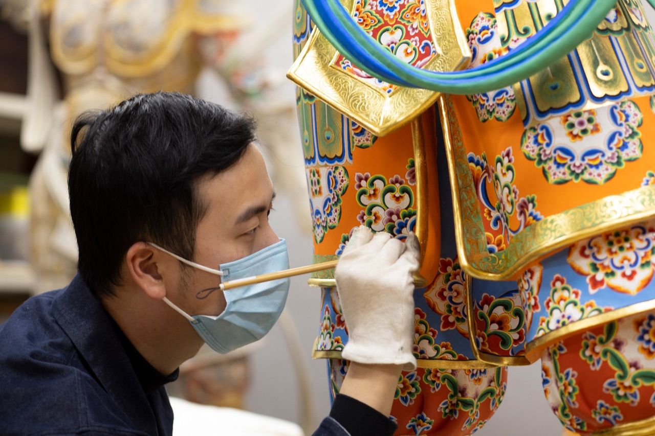 Cho Hinbun, a nihonga (Japanese painting) artist and graduate of the Tokyo University of the Arts, is on the coloring staff. Here he puts finishing touches on a statue. While working in physically awkward positions, he pays careful attention to the statue’s legs and other inconspicuous places. (© Kawamoto Seiya)