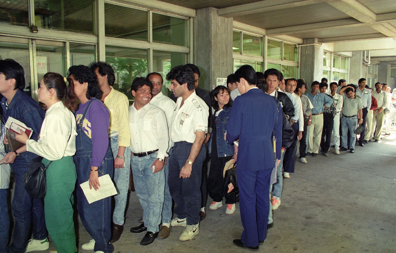 Foreign nationals line up outside the Tokyo immigration office (then in Ōtemachi) in May 1989 to secure documentation for voluntary repatriation in advance of tighter restrictions on foreign workers under the newly revised Immigration Control Law.