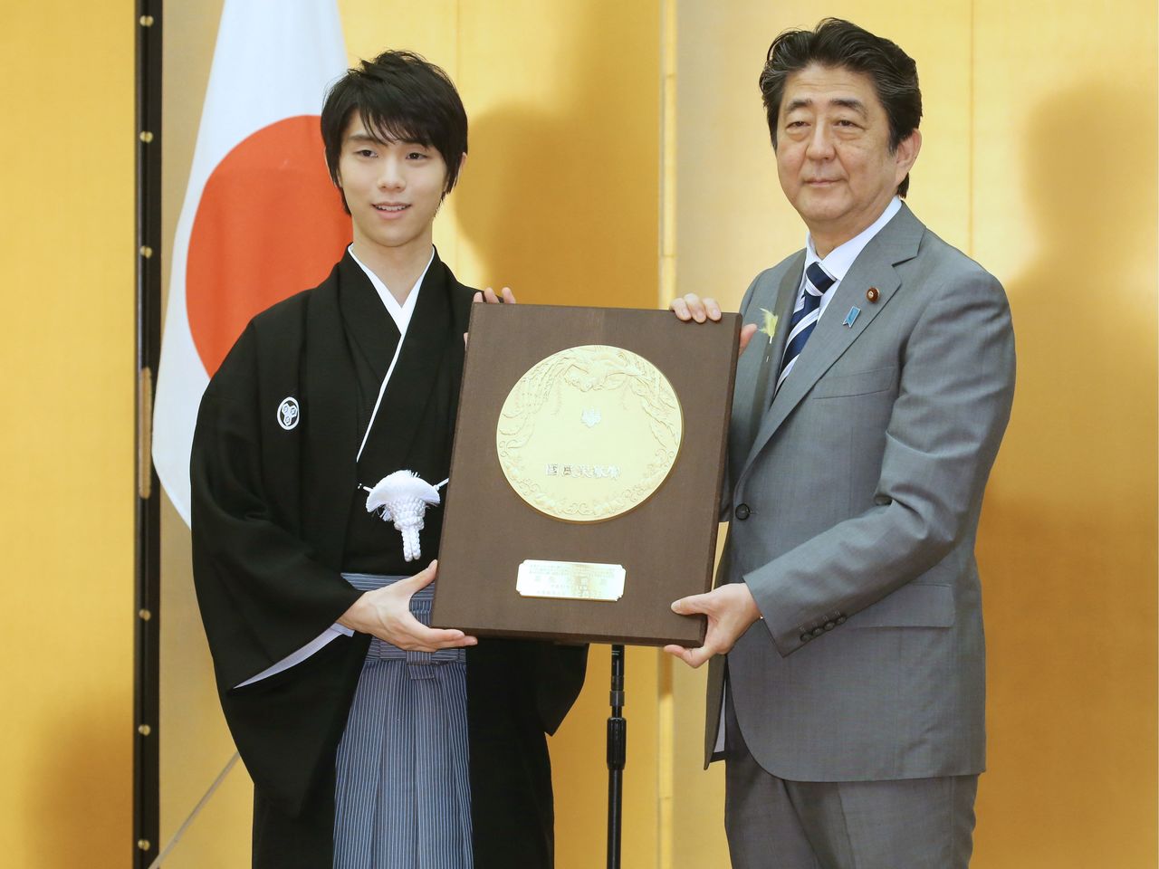 Hanyū Yuzuru (left) receives the People’s Honor Award from Prime Minister Abe Shinzō on July 2, 2018, for his achievement in winning successive gold medals at the Winter Olympics. (© Jiji)