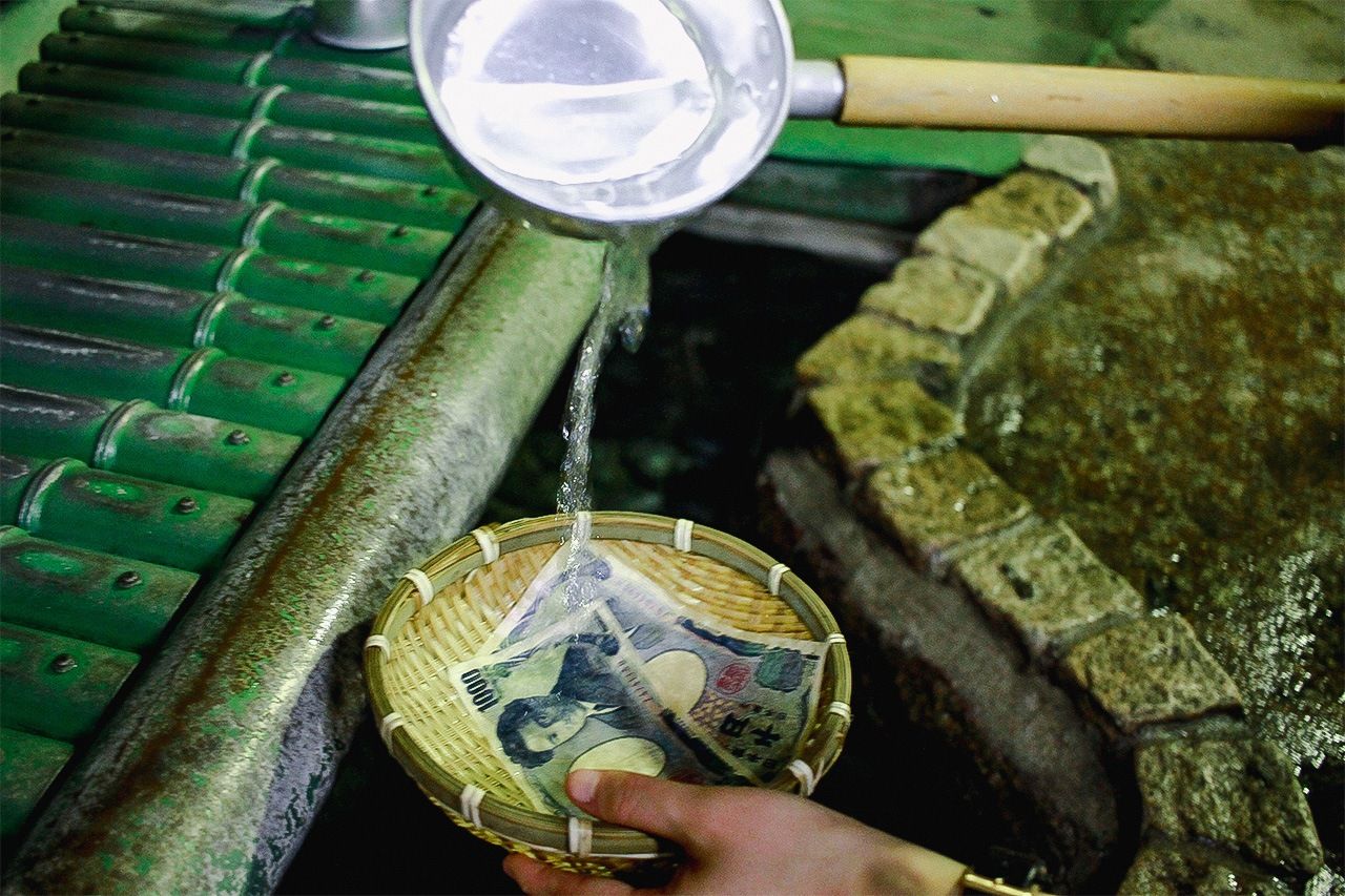 Washing money in the hope of increasing financial fortune. (© Pixta).