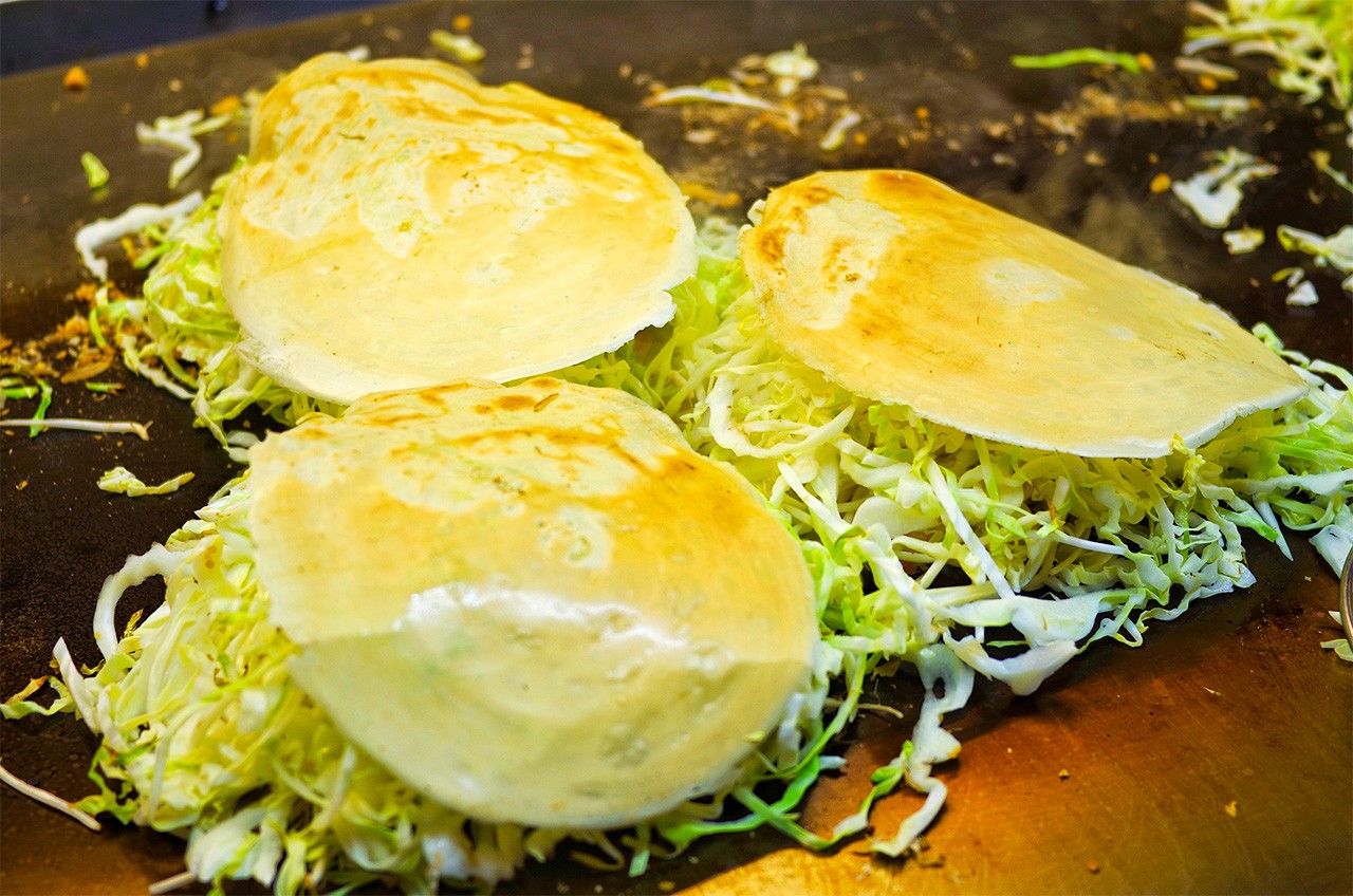 The cooked batter forms a lid over the cabbage and other ingredients to steam-bake them. (© Pixta)