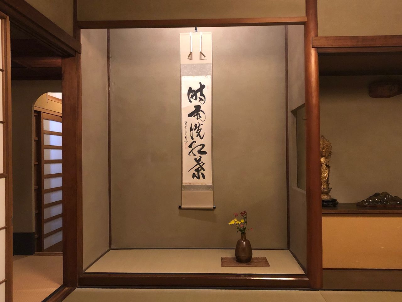 A flower arrangement and hanging scroll decorate a tokonoma. 