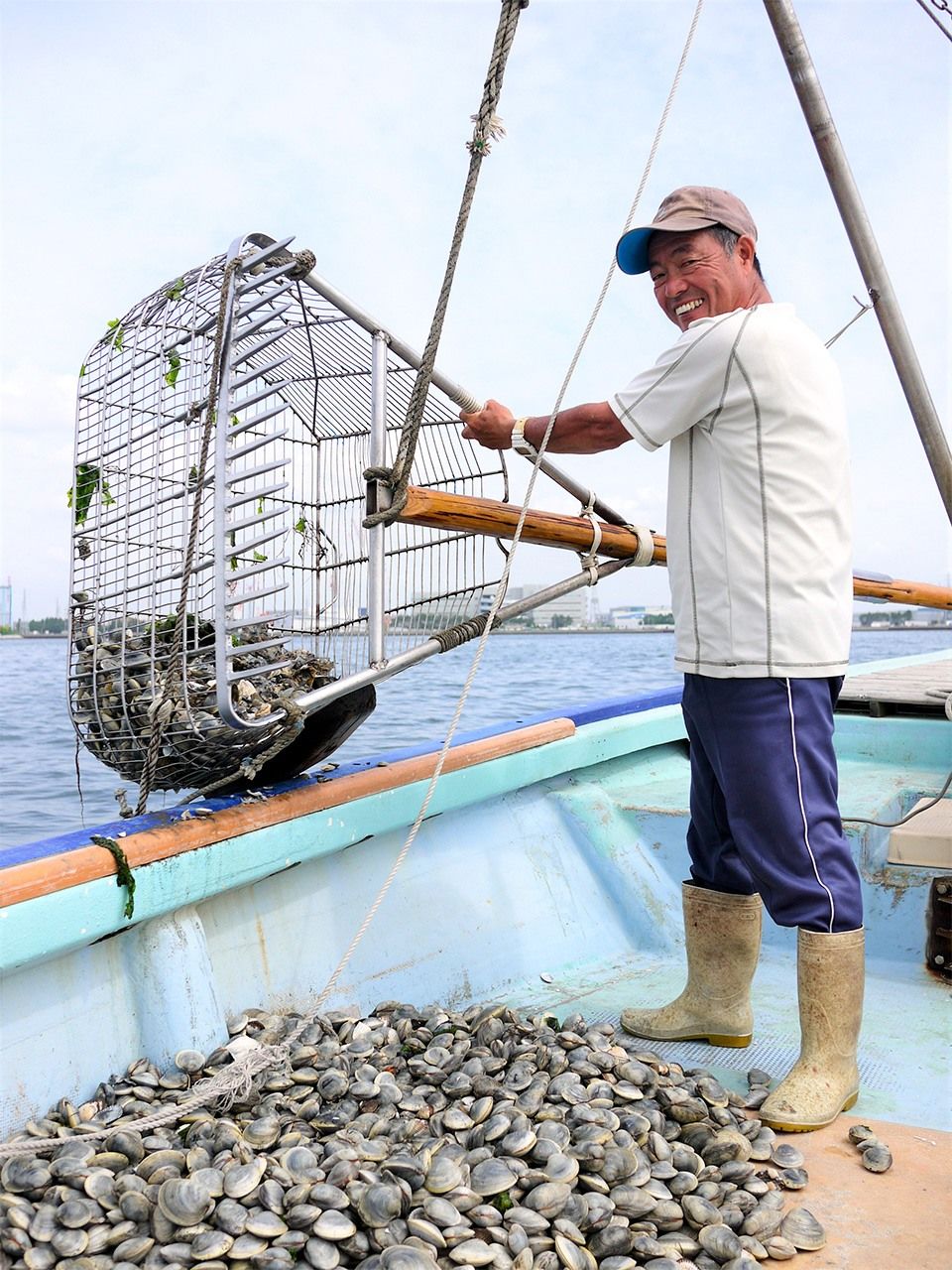 Fisherman Sawada Yōichi uses his boat and a professional-grade clam rake to dig for quahogs off of Funabashi in Chiba Prefecture.