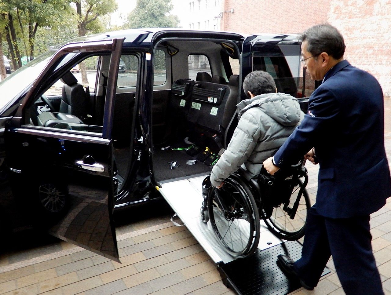 A passenger in Nagoya boards Toyota’s Japan Taxi on January 31, 2019, using the improved ramp. (© Jiji)