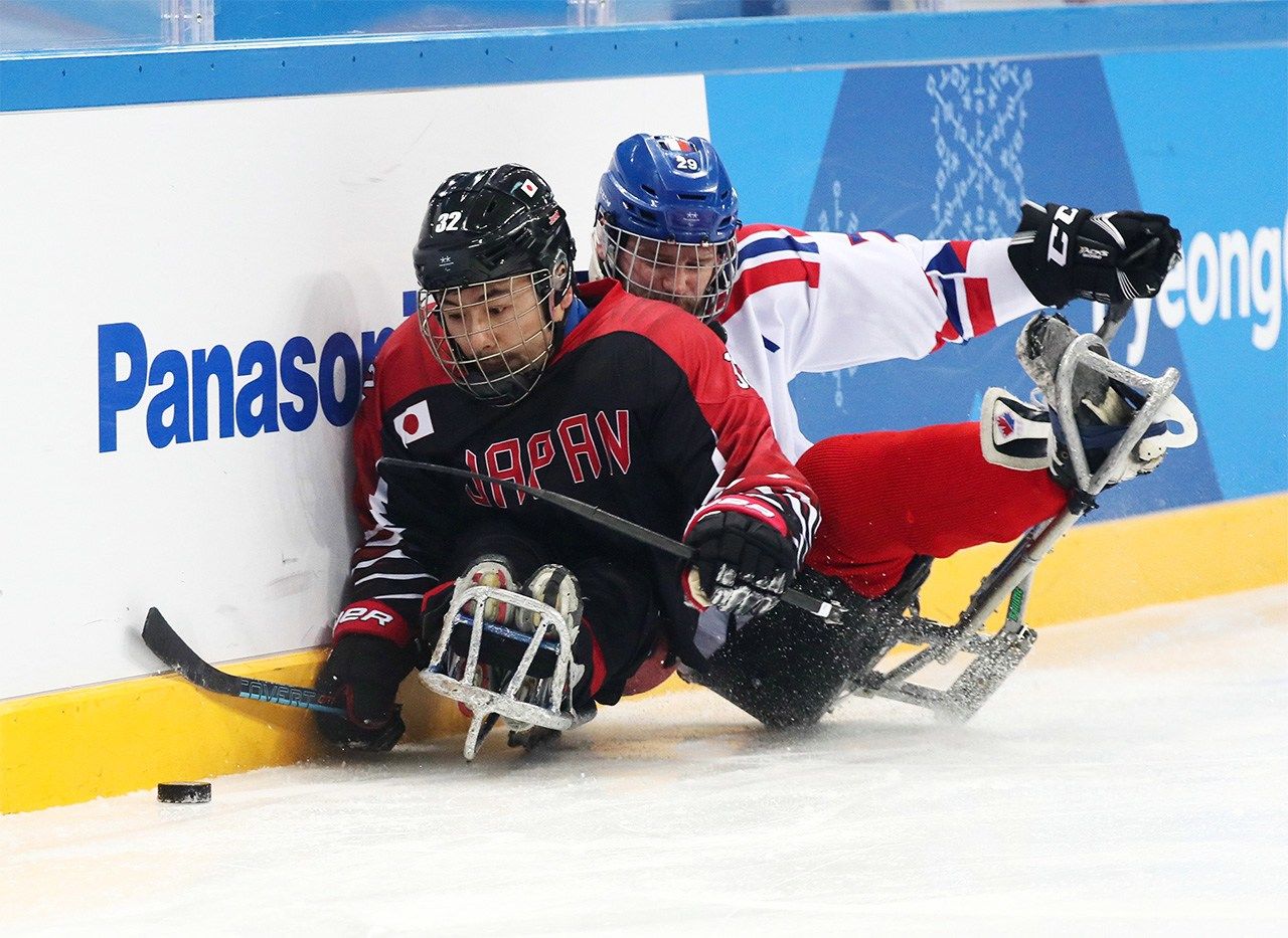 Uehara Daisuke (left) battles for the puck against a Czech Republic player on March 13, 2018, in the first round of ice sledge hockey at the Pyeongchang Winter Paralympics. (© Jiji)