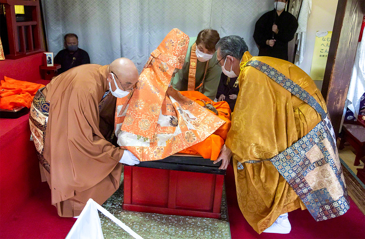 Priests at Dainichibō change the robes of sokushinbutsu Shinnyokai Shōnin. The ceremony takes place every year of the ox, according to the 12-year zodiac cycle. The old garments are cut up and given to people in attendance as talismans. (© DEGAM Tsuruoka Tourism Bureau)