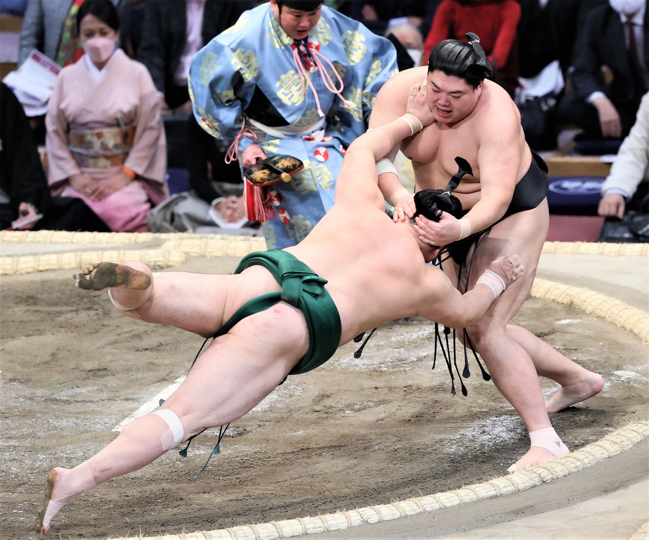 Tokkuri-nage (two-handed head twist-down): Using a pincer motion, Abi (right) grasps Satanoumi’s head and neck in both hands to force him down on the sixth day of the November 2021 basho. The name of this kimarite comes from using one’s thumb and forefinger to grasp the neck of a tokkuri sake flask. © Jiji