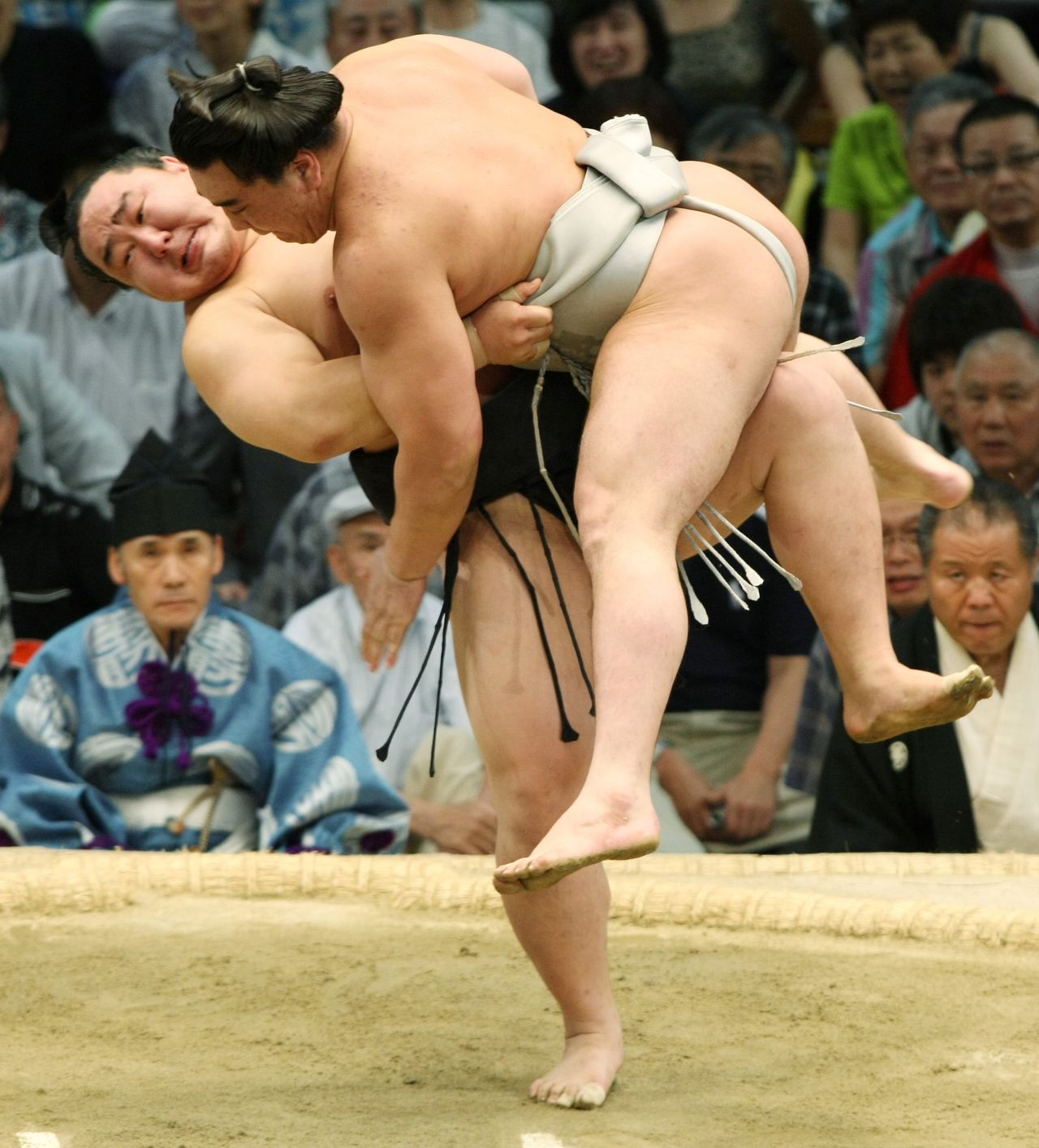 At the July 2009 basho, Mongolia-born Asashōryū (left) lifts Harumafuji atop his leg and, using a left upper arm throw, pulls off a yaguranage. Interviewed after the match, Asashōryū said that the move was the same as one used in Mongolian wrestling, and that he had been planning for a while to use it. (© Jiji)