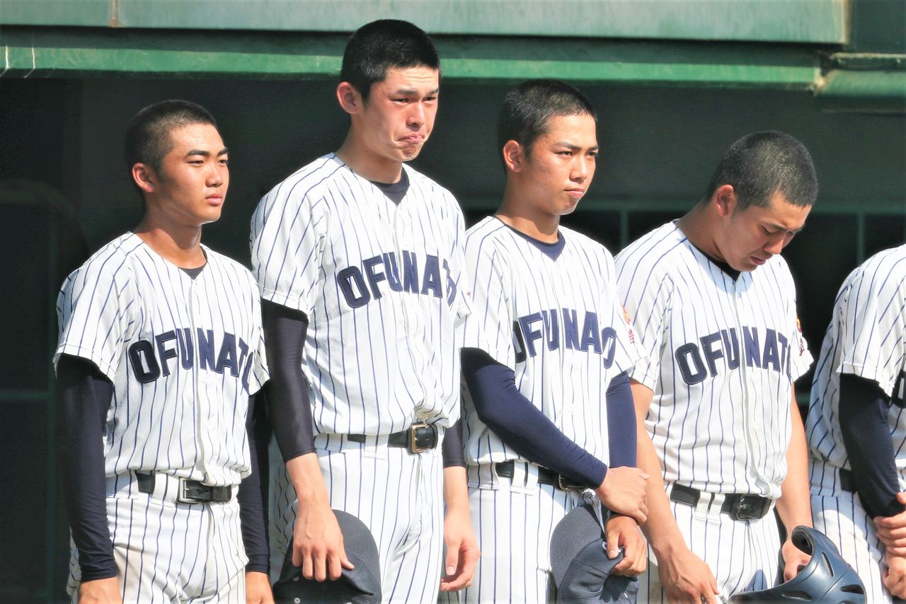 Sasaki, second from left, and his teammates stand teary-eyed outside the dugout following Ōfunato’s loss to Hanamaki Higashi in the finals of the Iwate high school baseball tournament at the prefectural baseball stadium on July 25, 2019. (© Jiji)